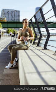 Pretty young woman with earphones takes a break after running in the urban area