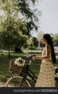 Pretty young woman with electric bike and flowers in the basket