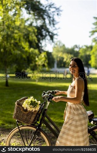 Pretty young woman with electric bike and flowers in the basket