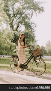 Pretty young woman with electric bike and flowers in the basket