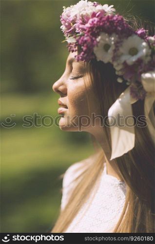 Pretty young woman with flowers in a hair on a sunny spring day