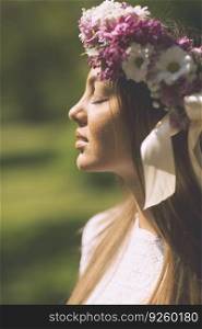 Pretty young woman with flowers in a hair on a sunny spring day