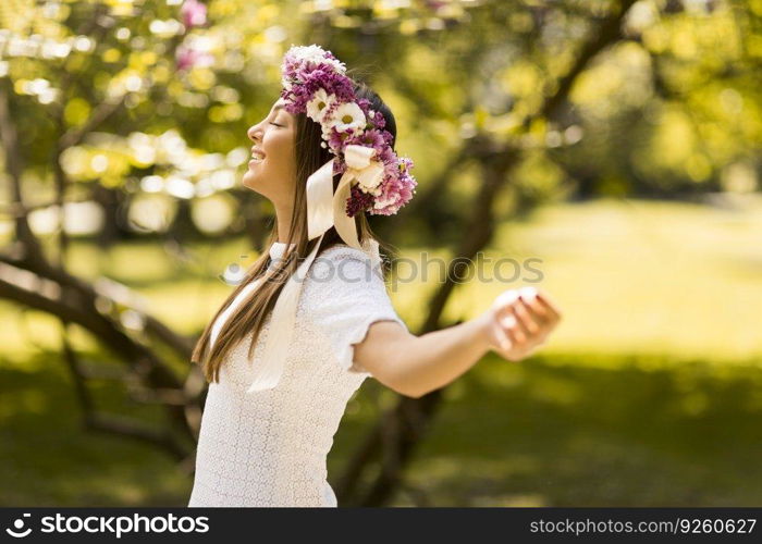 Pretty young woman with flowers in her hair on sunny spring day