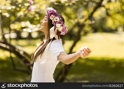 Pretty young woman with flowers in her hair on sunny spring day