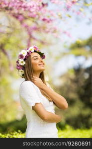 Pretty young woman with flowers in her hair on sunny spring day