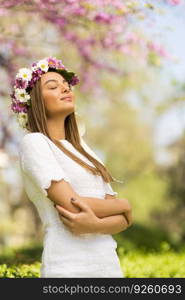 Pretty young woman with flowers in her hair on sunny spring day