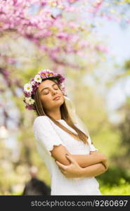 Pretty young woman with flowers in her hair on sunny spring day