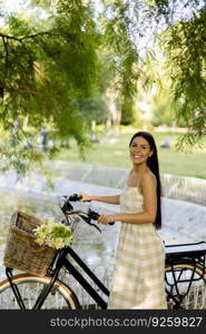 Pretty young woman with flowers in the basket of electric bike