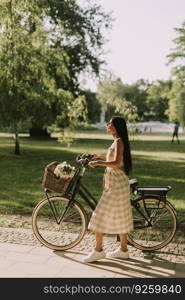 Pretty young woman with flowers in the basket of electric bike