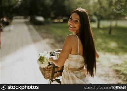 Pretty young woman with flowers in the basket of electric bike