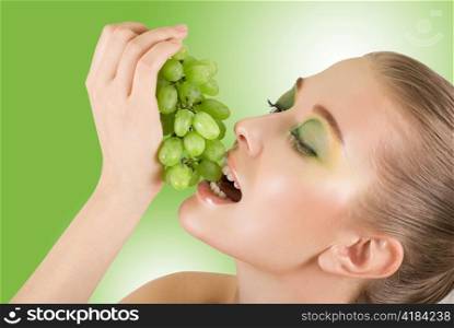 Pretty young woman with grape closeup on the green background