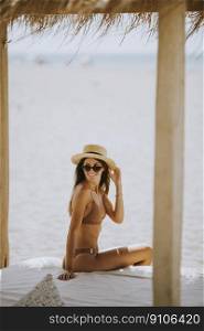 Pretty young woman with hat and sunglasses relaxing in the beach lounge