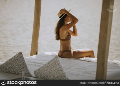 Pretty young woman with hat and sunglasses relaxing in the beach lounge