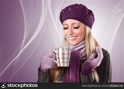 pretty young woman with hat, scarf and gloves ready for a cold winter and keeping a hot cup of tea