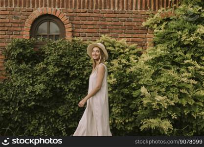 Pretty young woman with hat walking in the resort garden