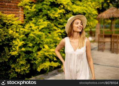 Pretty young woman with hat walking in the resort garden