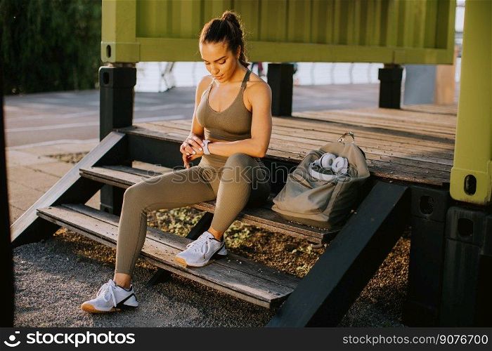 Pretty young woman with headphones  taking a break during outdoor exercisin