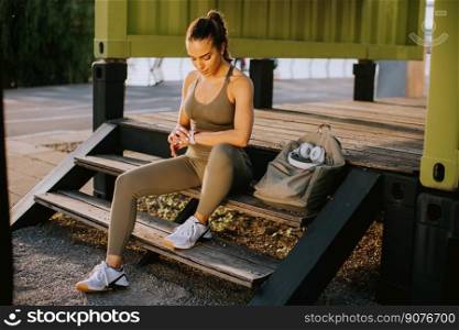 Pretty young woman with headphones  taking a break during outdoor exercisin
