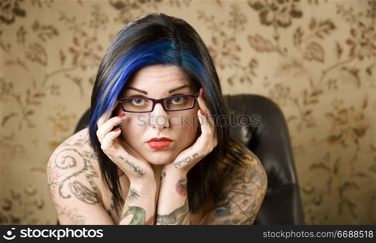Pretty young woman with many tattoos in a leather chair