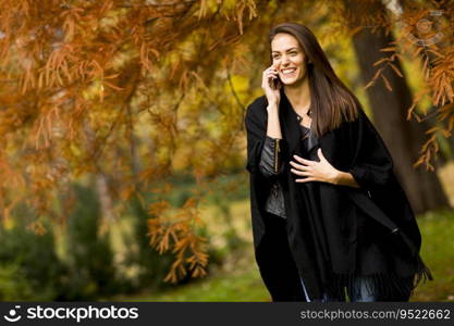 Pretty young woman with mobile phone in autumn park