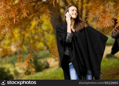 Pretty young woman with mobile phone in autumn park