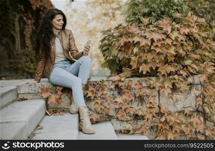 Pretty young woman with mobile phone on autumn day