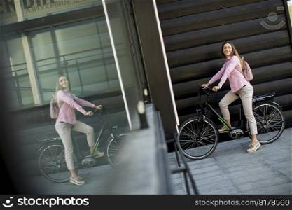 Pretty young woman with modern city electric e-bike as clean sustainable urban transportation