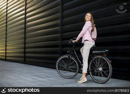 Pretty young woman with modern city electric e-bike as clean sustainable urban transportation