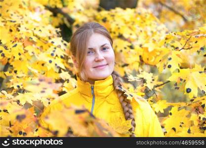 Pretty young woman with red hair in the autumn park with yellow fallen leaves
