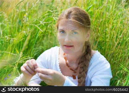 Pretty young woman with red hair on the green grass field