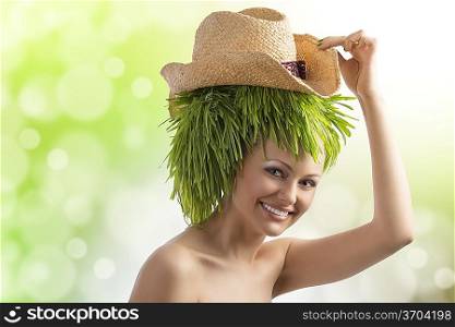 pretty young woman with summer hat and hair style done with some green grass smiling on color background