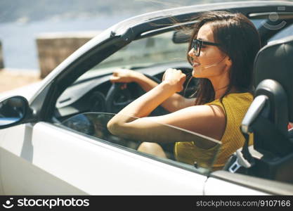 Pretty young woman with sunglasses driving in white cabriolet car