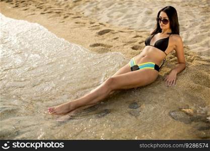 Pretty young woman with sunglasses lying on the beach