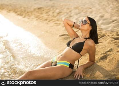 Pretty young woman with sunglasses lying on the beach