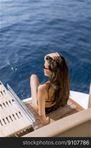 Pretty young woman with sunglasses relaxing on the yacht on sea at sunny day