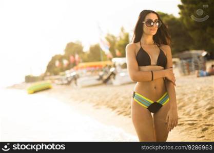 Pretty young woman with sunglasses walking on the beach at summer