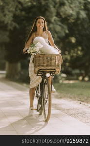 Pretty young woman with white bichon frise dog in the basket of electric bike