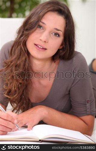 Pretty young woman writing in a book