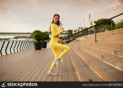 Pretty young womantaking exercises on the stairs by the river promenade