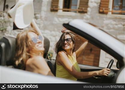 Pretty young women driving and having fun in white cabriolet car