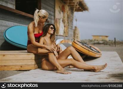 Pretty young women in bikini sitting by the surf cabin on a beach at summer day