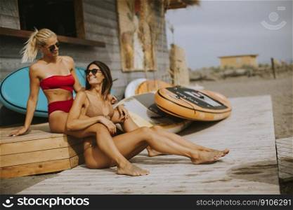 Pretty young women in bikini sitting by the surf cabin on a beach at summer day