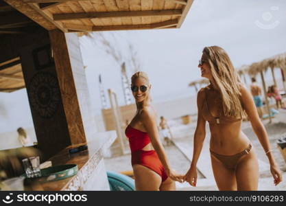 Pretty young women in bikini walking by the surf cabin on a beach at summer day