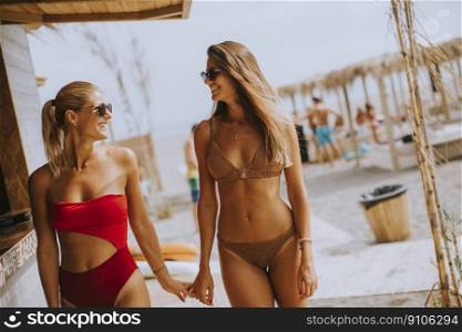 Pretty young women in bikini walking by the surf cabin on a beach at summer day