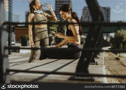 Pretty young women in sportswear exercising on a river promenade