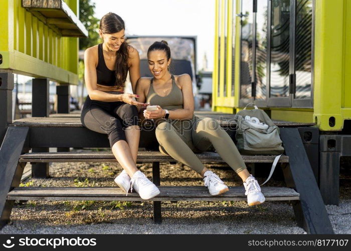 Pretty young women in sportswear looking at mobile phone after exercise training