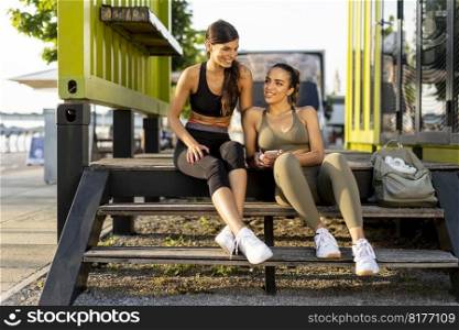 Pretty young women in sportswear looking at mobile phone after exercise training