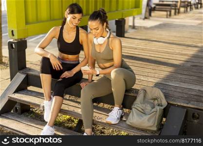 Pretty young women in sportswear looking at mobile phone after exercise training