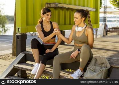 Pretty young women in sportswear taking a rest after exercising on a river promenade