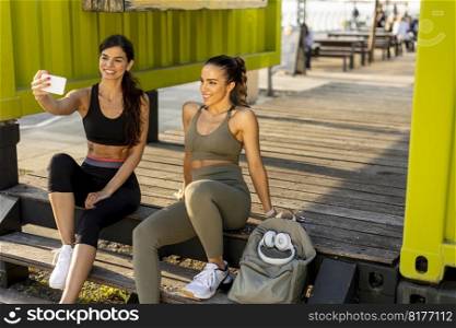 Pretty young women in sportswear taking selfie with mobile phone after exercise training